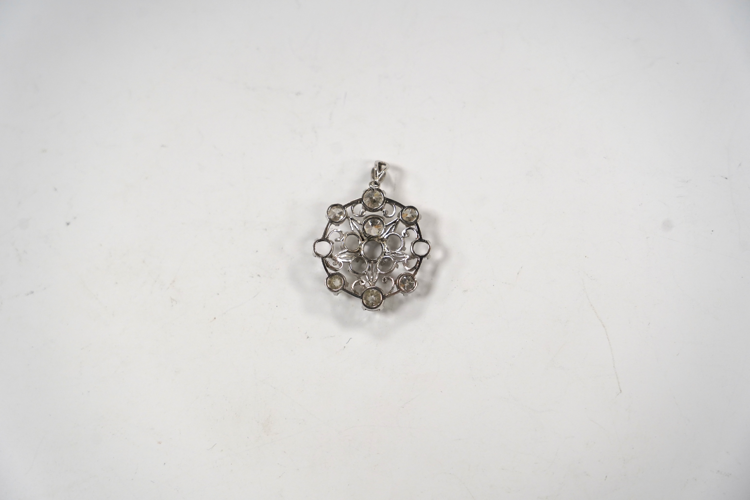 A white metal and diamond cluster set circular pendant (seven stones missing), largest stone diameter approx. 5.6mm, overall 35mm, gross weight 6 grams.